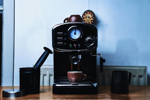 A black coffee maker machine in the process of making coffee