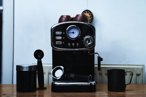 A black coffee maker machine with a mug on the table
