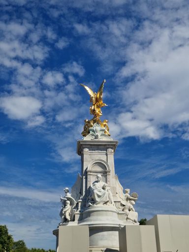 A low angle shot of Victoria Memorial against a cloudy blue sky in London, England
