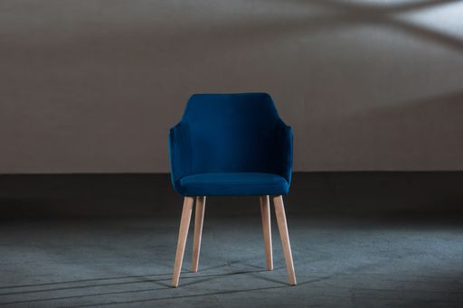 A blue dining room chair in a studio with gray walls