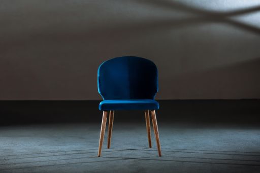A blue dining room chair in a studio with gray walls