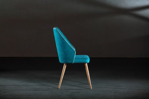A blue dining room chair in a studio with gray walls