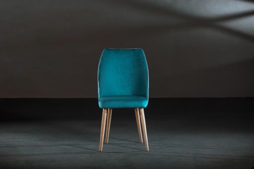 A comfy blue wing chair in a studio with gray walls