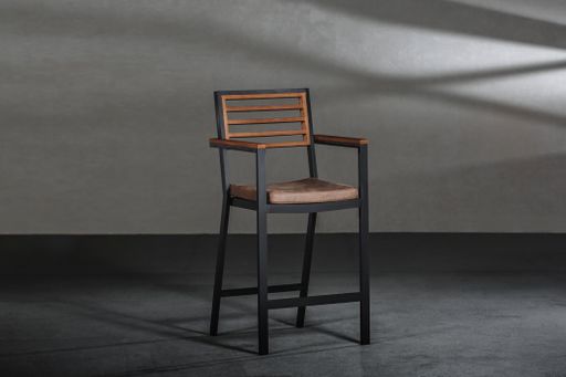 A simple chair with metallic high legs in a room with gray walls