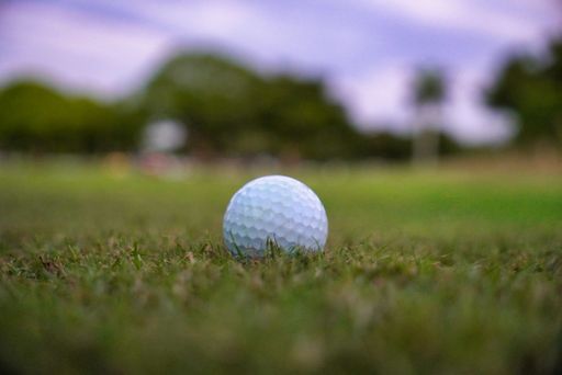 A closeup of a single golf ball on the grass at a golf field