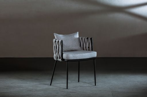A closeup of a small comfortable chair with a gray cushion on it in a room