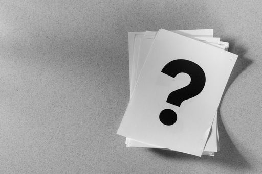 A grayscale shot of a pile of papers with a printed question mark - the concept of brainstorming