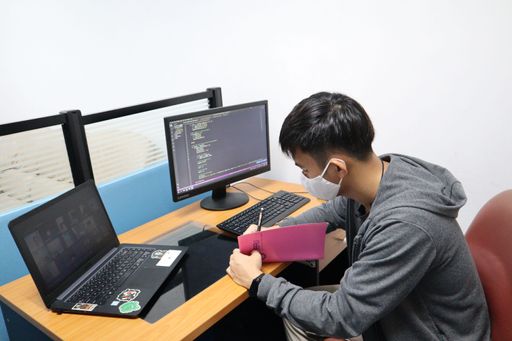 A young boy in a mask learning coding on his computer during the pandemic