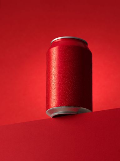 A vertical shot of a red soda can with water drops