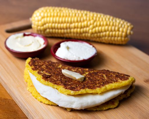 A closeup of cachapa with cheese and boiled corn on the background