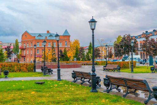 City park in old part of city. Ancient buildings, lanterns and fountain. Autumn colors. Cloudy skies and rain.