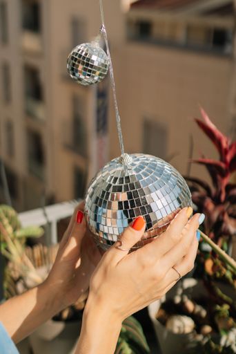The Caucasian female hands holding a silver disco ball