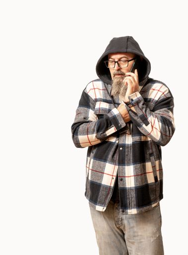 A bald middle-aged man in a checkered jacket is talking on a mobile phone