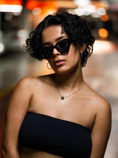 A vertical portrait of a stylish young female with fancy sunglasses wearing a short strapless top