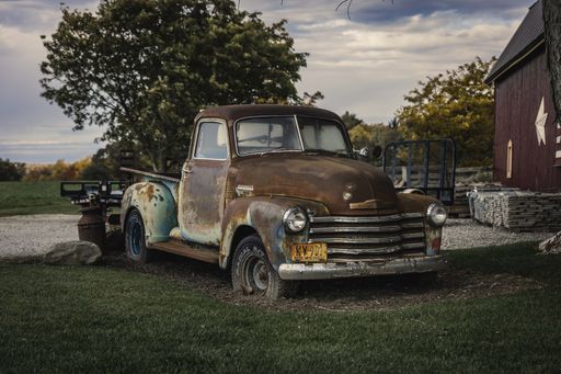 A closeup shot of an old rusty Chevrolet 3100 car in the farm