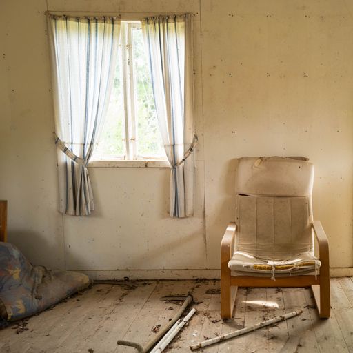 An old abandoned dirty room with aged armchair, floor and window