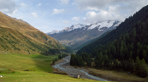 A beautiful shot of a valley with a flowing stream in the Italian Alps