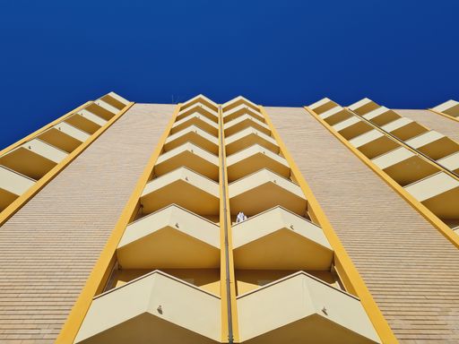 A low angle shot of a geometrically shaped building with balconies on a sunny day