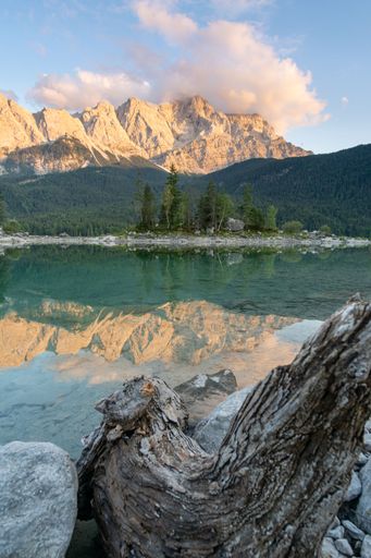 A vertical shot of a lake with a mountain range on the shore on a sunny day