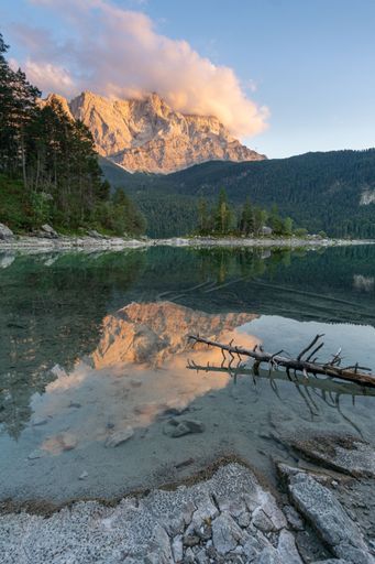 A vertical shot of a lake with a mountain range on the shore on a sunny day