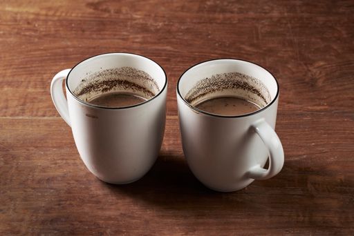 Two glasses of brewed milk coffee served on a wooden table