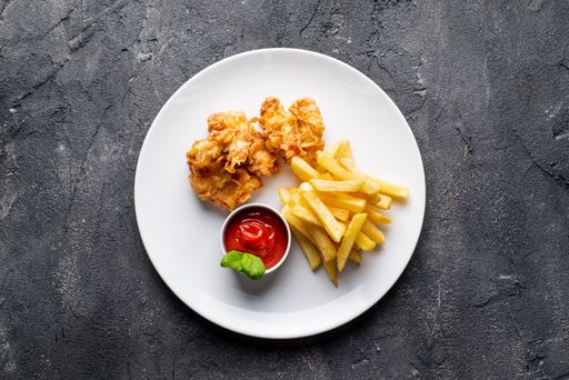 A top view of aesthetically decorated delicious chicken nagets with french fries on the gray surface