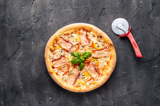 A top view of aesthetically decorated delicious pizza on the gray surface