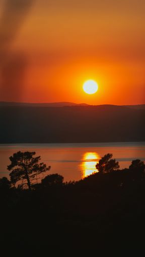 A vertical image of water surface below the sun during golden hour in Dalmatia, Croatia