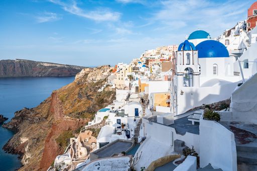The village of Oia with white cave houses and churches with blue domes overlooking the beautiful sea