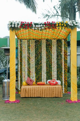 Colourful pastel elegant decor wedding venue set up outdoors with orchid flowers and colourful table sheet for India wedding reception.