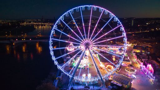 A drone shot of a colorful glowing Ferris wheel in the old town of Dresden, Germany