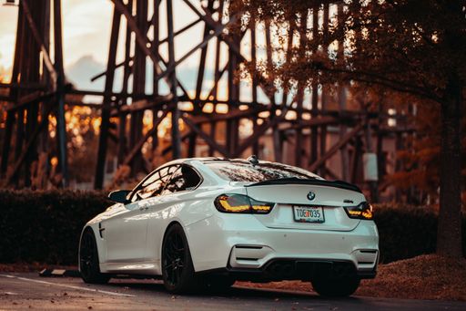 A white BMW M4 parked in front of a bridge