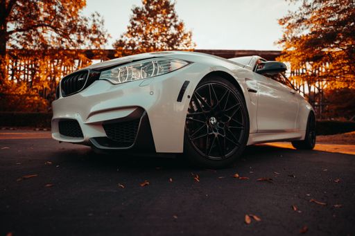 Front view of a modern white BMW M4 on the street during an autumn sunset. Luxury sports car