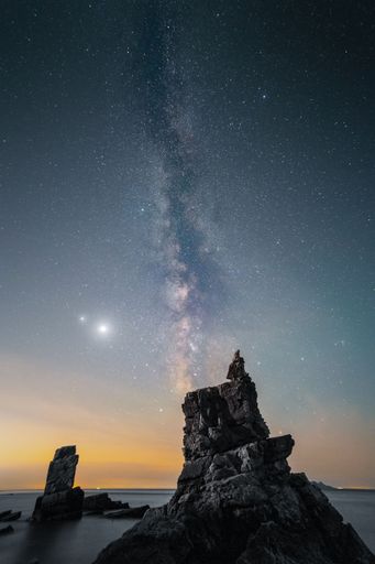 A person admires the tranquil beauty of the milky way galaxy sky from a cliff in Dalian, Liaoning