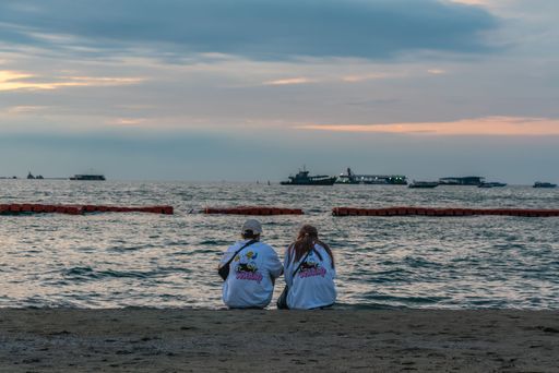 Couple sitting by the beach and enjoying the sunset view in Pattaya, Thailand. Horizontal Shot,