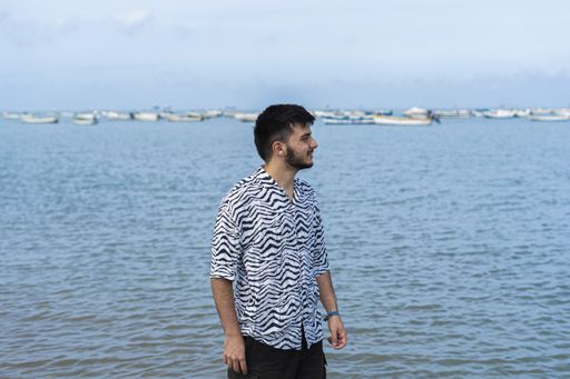A Hispanic man wearing protective mask while enjoying the view at a beach on a sunny day
