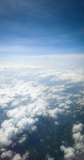 A vertical shot of puffy white clouds in the sky from above