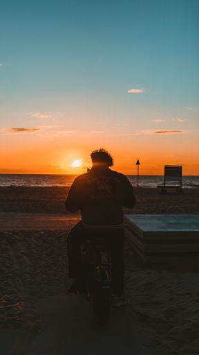 A silhouette of man watching sunset scenery from seashore