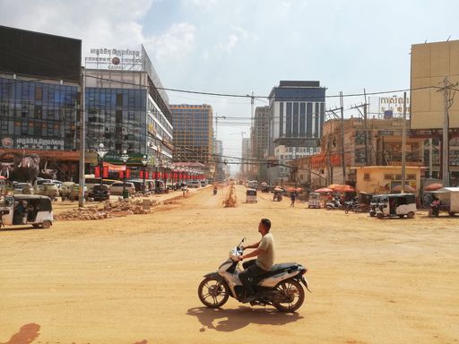 A man on a scooter driving through the dusty city of Sihanoukville in Cambodia