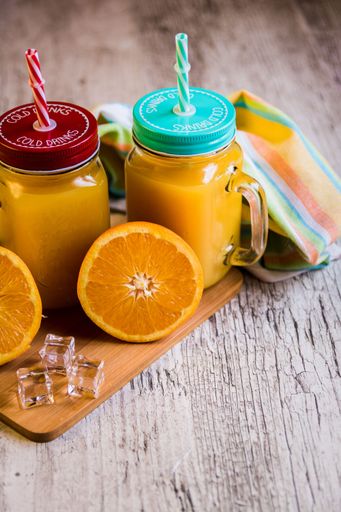 The Mason jar with orange lemonade on the table, close-up